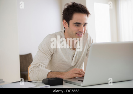 Mid adult man using laptop, smiling Stock Photo