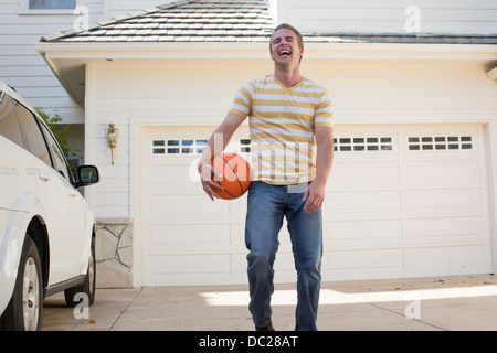 Young man holding basketball laughing, portrait Stock Photo