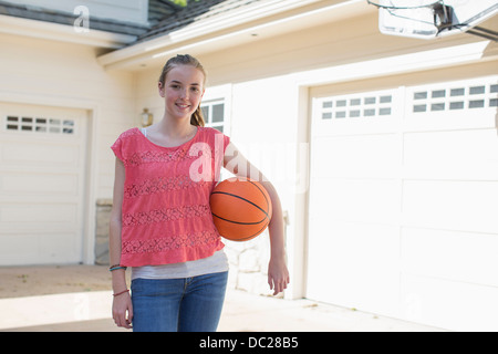 Teenage girl holding basketball, portrait