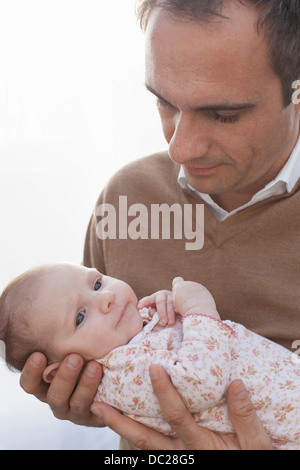 Father holding newborn baby daughter