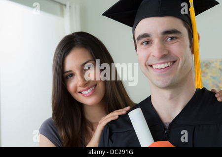 Man wearing mortarboard and graduation gown with woman Stock Photo
