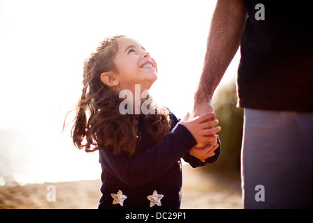 Girl holding father's hand, looking up