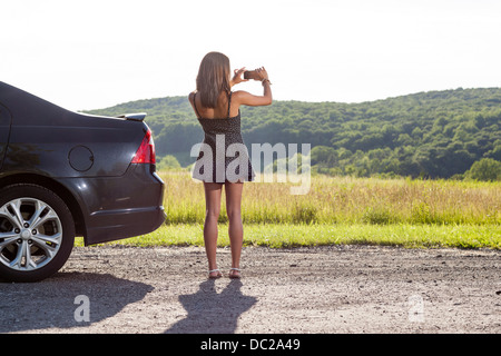 Young woman photographing rural scene with camera phone Stock Photo