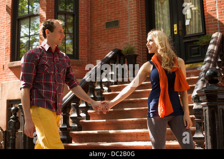Couple walking hand in hand past outdoor stairs Stock Photo