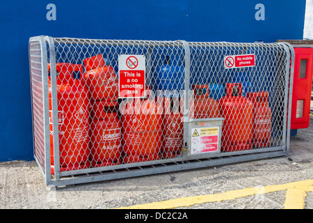 Gas bottles being stored in a cage with no smoking sign Stock Photo