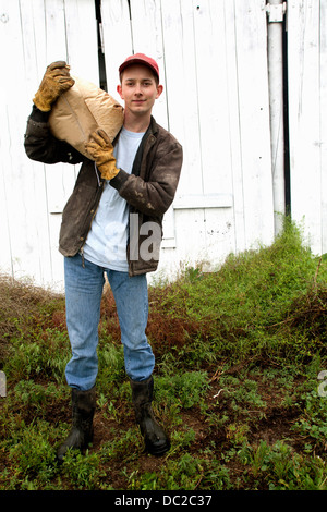 Farmer with sack of feed on shoulder Stock Photo