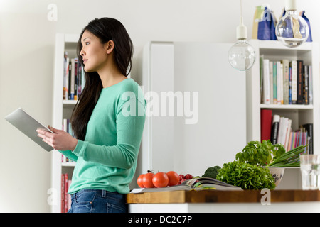 Profile of woman holding digital tablet leaning against table Stock Photo