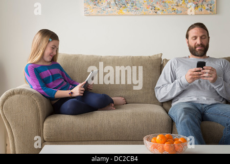 Father and daughter sitting on couch Stock Photo