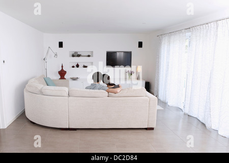 Husband and wife relaxing on corner sofa in living room Stock Photo