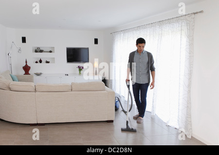 Man vacuuming living room floor Stock Photo