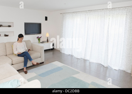 Woman reading in living room Stock Photo