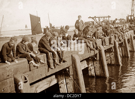 Boys fishing on a pier early 1900s Stock Photo