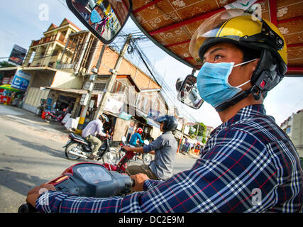 Phnom Penh, Cambodia. 3rd Jan, 2013. Jan 3, 2013 - A Tuk Tuk driver uses a surgical mask, which does little to filter out harmful particles and gases in air pollution, navigates traffic through the Cambodian capital city of Phnom Penh.Story Summary: It is said that the battle over global warming is to be won or lost in Asia. Stock Photo