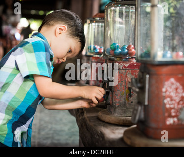 Series of photos of a 2 year old mixed race Asian Caucasian child enthusiastically getting a toy from a vintage vending machine Stock Photo