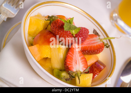 Fresh fruit salad dessert in white gold rimmed porcelain bowl. Stock Photo