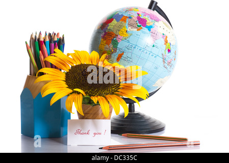 globe with pencils and a sunflower on a white background Stock Photo