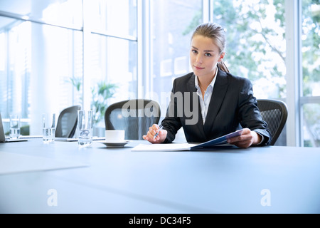 Portrait of serious businesswoman reviewing paperwork in conference room Stock Photo