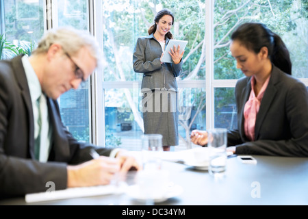 Smiling woman using digital tablet at window in conference room Stock Photo