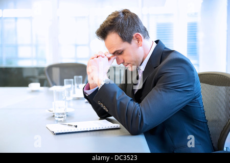 Businessman with head in hands in conference room Stock Photo