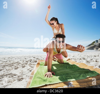 Woman piggybacking enthusiastic man on beach Stock Photo