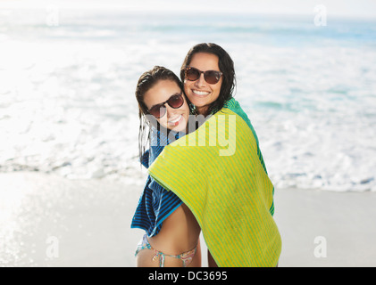 Portrait of smiling friends wrapped in towel on beach Stock Photo