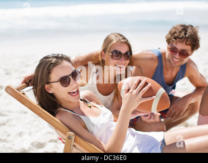 Smiling friends with football on beach Stock Photo