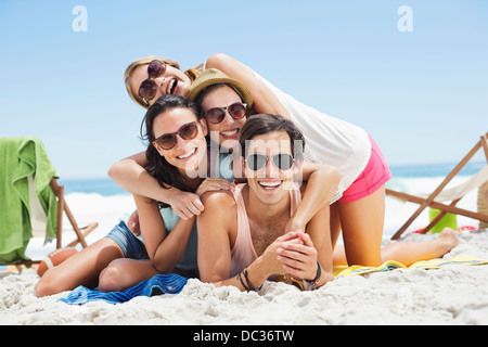 Portrait of happy friends laying on top of each other on beach Stock Photo
