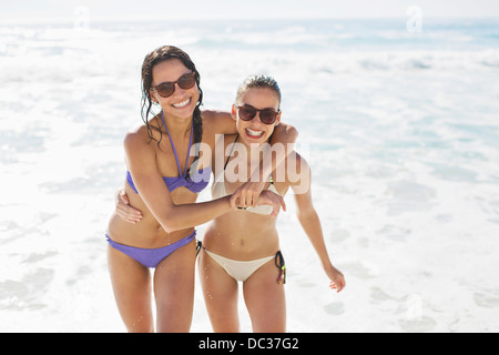 Portrait of enthusiastic friends in bikinis hugging on beach Stock Photo