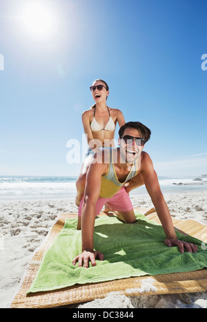 Enthusiastic couple piggybacking on beach Stock Photo