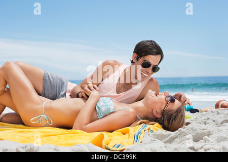 Happy couple laying on blanket at beach Stock Photo