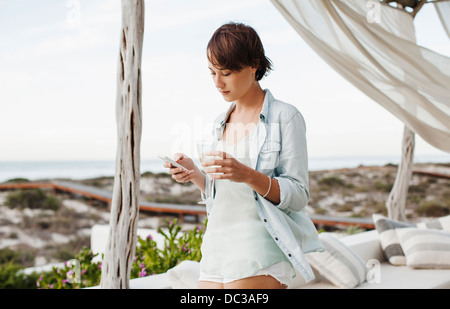 Woman drinking wine and text messaging with cell phone on patio Stock Photo