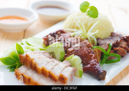 Roasted duck, roasted pork crispy siu yuk and Charsiu Chinese style, served with steamed rice on dining table. Singapore cuisine. Stock Photo