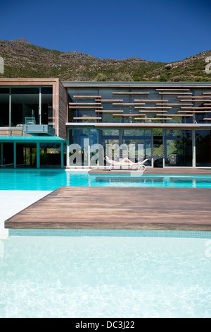 Woman sunbathing poolside of modern house Stock Photo