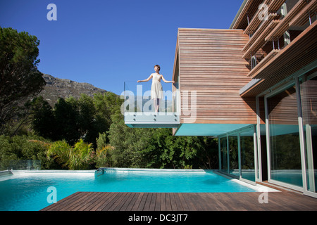 Woman standing on balcony over swimming pool Stock Photo