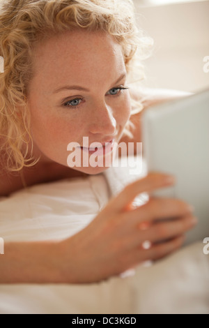 Close up of woman laying in bed using digital tablet Stock Photo