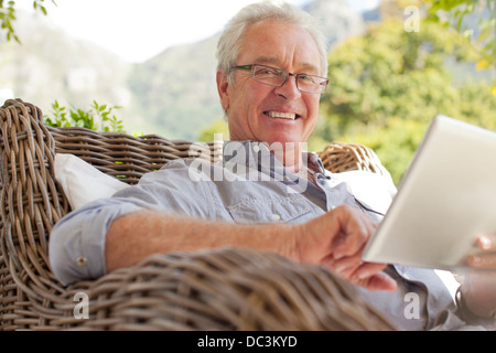Portrait of smiling man using digital tablet on patio Stock Photo