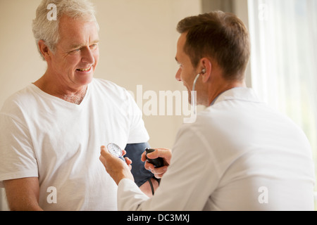 Doctor checking senior man's blood pressure in doctor's office Stock Photo