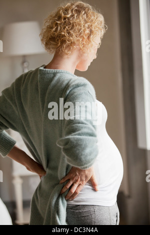Pregnant woman holding back in pain Stock Photo