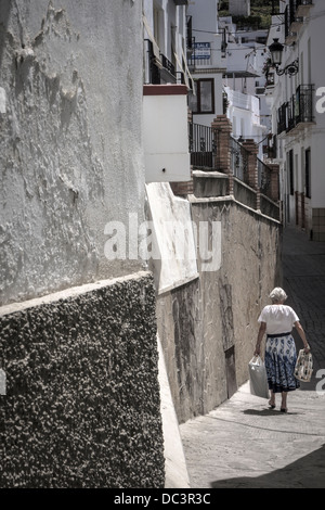 A lady makes her way along one of the winding whitewashed streets of Competa in Andalusia, southern Spain. Stock Photo