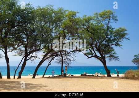 Makena Beach with view to Kahoʻolawe under some trees in Maui, Hawaii. Several people enjoying the day on the beach. Stock Photo