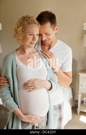 Smiling man hugging pregnant woman Stock Photo