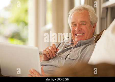 Portrait of smiling senior man using laptop on porch Stock Photo