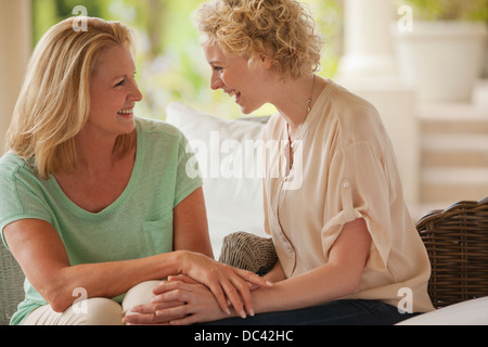 Smiling mother and daughter holding hands on porch Stock Photo