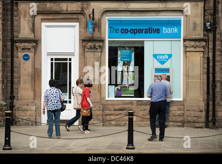 People queuing to use the cashpoint machine outside the co-operative bank in Matlock, Derbyshire Stock Photo