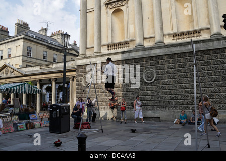 Man walking on tightrope whilst playing violin, Busker / Street Entertainer in Bath city centre England Busking Stock Photo