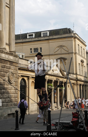 Man walking on tightrope whilst playing violin, Busker / Street Entertainer in Bath city centre England Stock Photo