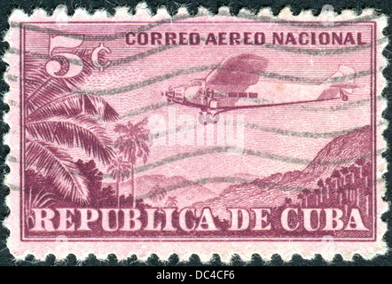 A postage stamp printed in Cuba, shows a airplane Ford 4-AT (The Tin Goose) over mountain landscape Stock Photo