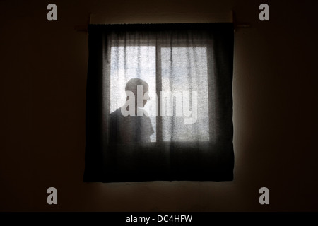 A man looking into a room through the window. Stock Photo