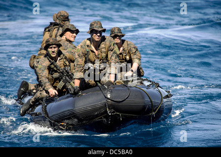 US Marines approach the well deck of the amphibious assault ship USS Bonhomme Richard in a combat rubber raiding craft following a simulated boat assault August 8, 2013 in the Coral Sea. Stock Photo