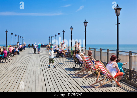 People sitting on deckchairs along the sides of the pier at Skegness Lincolnshire England UK GB EU Europe Stock Photo